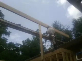 Carpenter setting a ridge beam over a new addition frame — Ice Dam Removal by Roofing Brothers in Riner