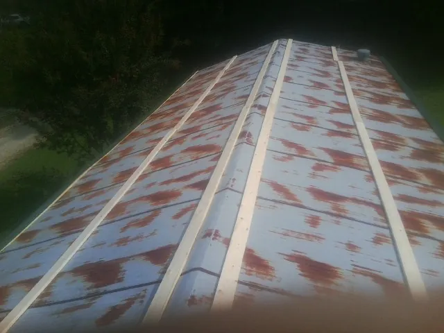 Rusted metal roof panels with new wood purlins before replacement — Storm Damage Roof Repair in Riner by Roofing Brothers
