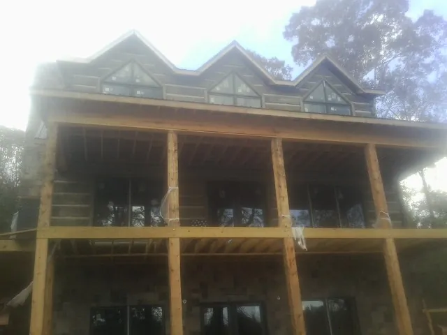 Dormers and porch framing on a large log home under construction — Roof Coating work by our crew in Riner