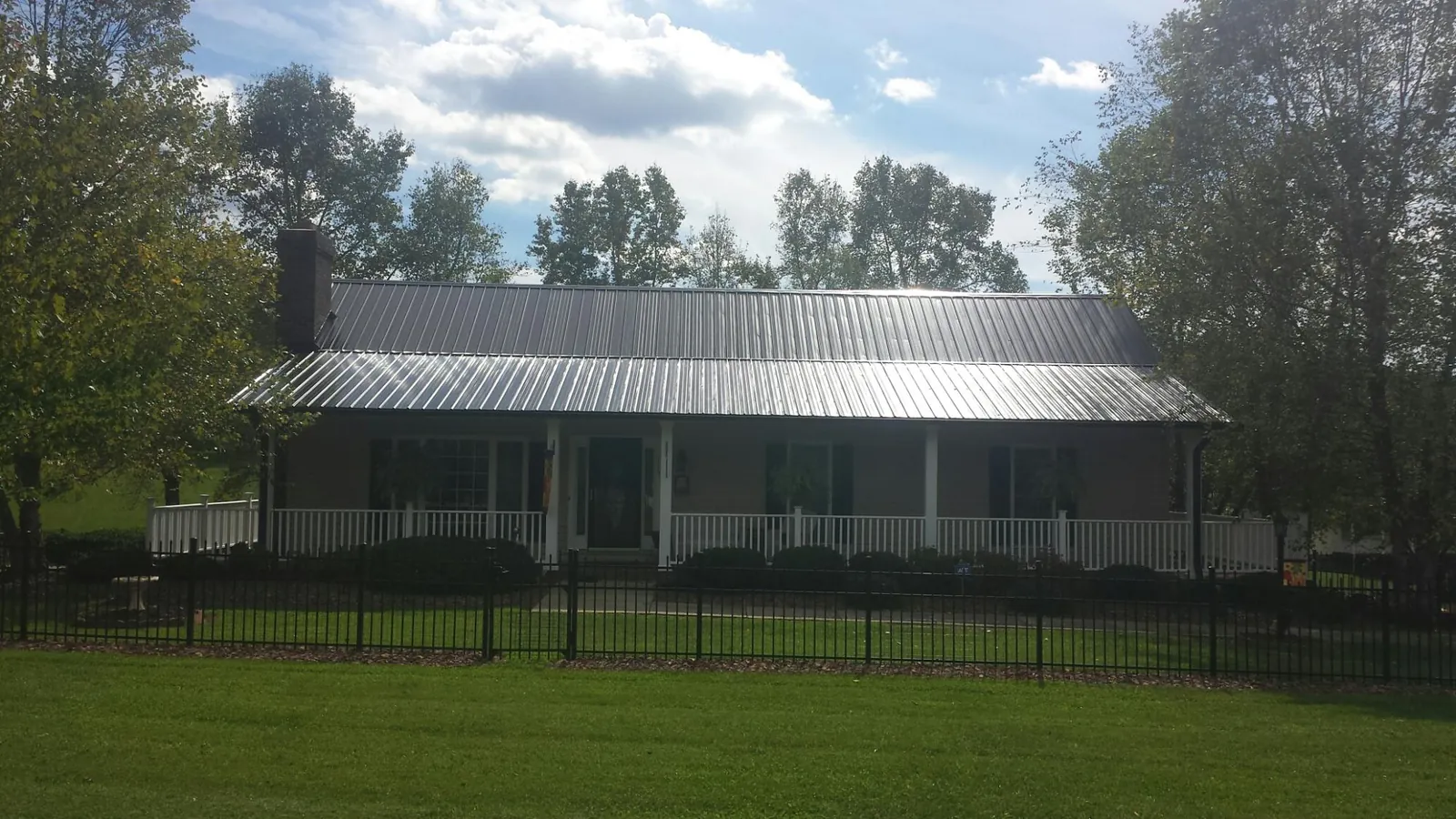 Gray metal roof on a brick ranch with a full width front porch — Gutter Guard Installation work by our crew in Riner