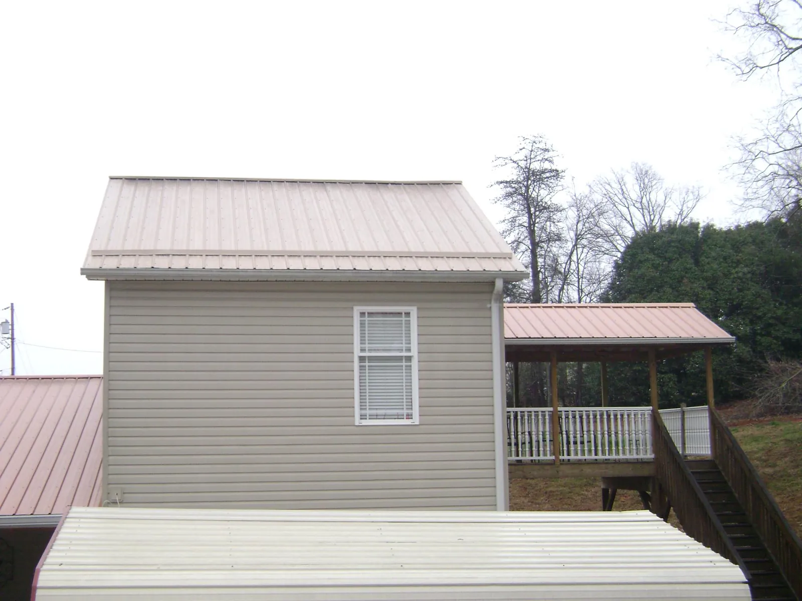 Tan metal roofs on a two story addition and attached porch, from a Roof Replacement job in Riner