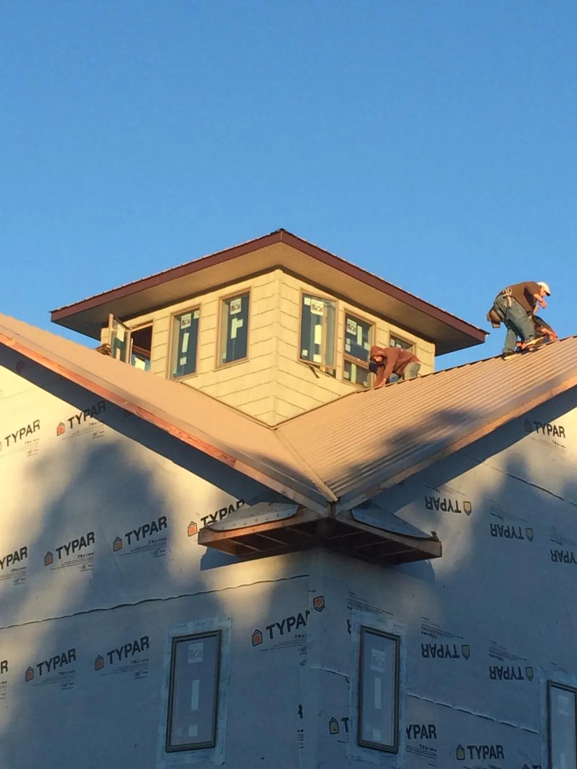 Roofers working around a rooftop cupola on a new metal roof at sunset — Roof Waterproofing in Riner by Roofing Brothers